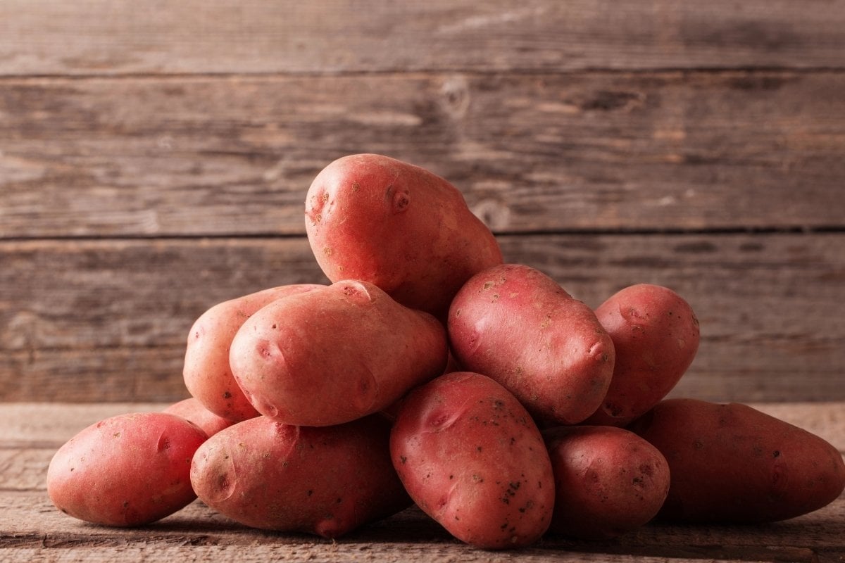 A pile of red potatoes on a wooden background.