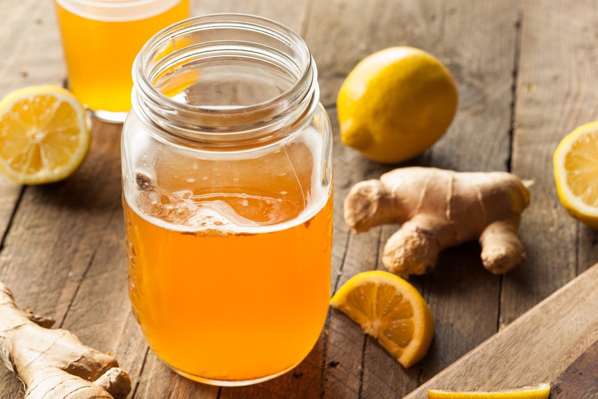 A mason jar with lemons and ginger on a wooden table.