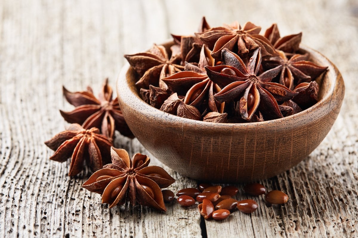 Star anise seeds in a wooden bowl on a wooden table.