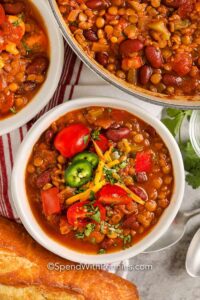 A bowl of chili with beans, tomatoes and bread.