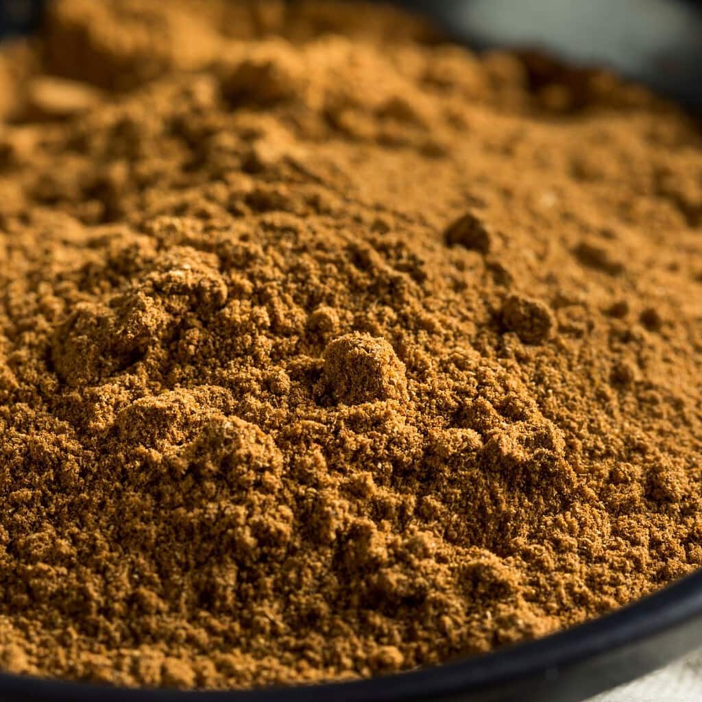 Cinnamon powder in a bowl on the table, perfect for Chinese five spice substitutes.