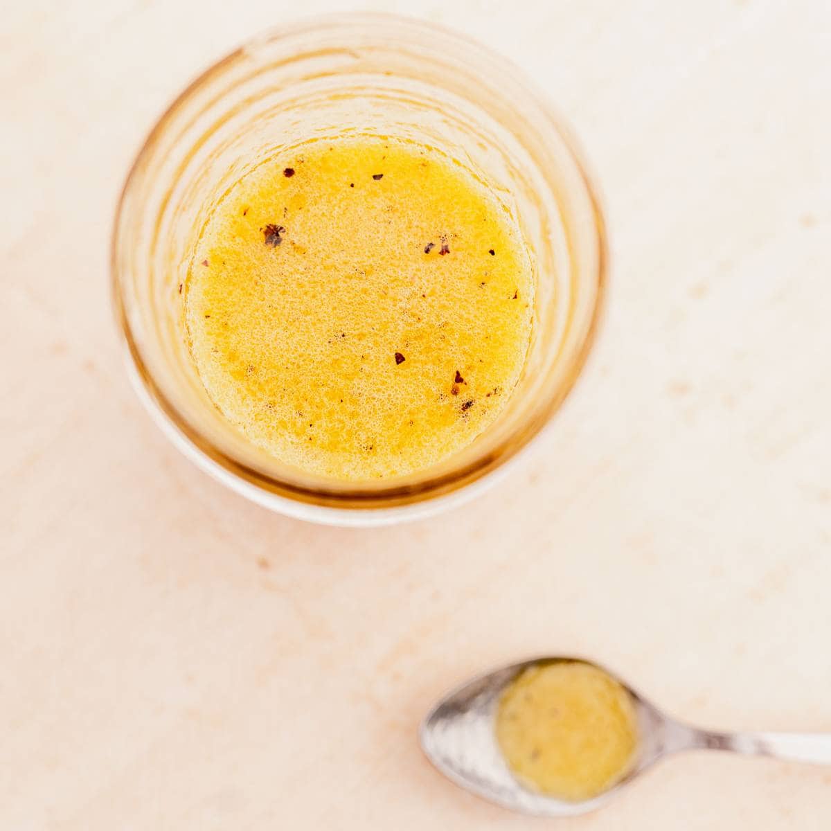 Top view of an open jar filled with a yellow salad dressing.