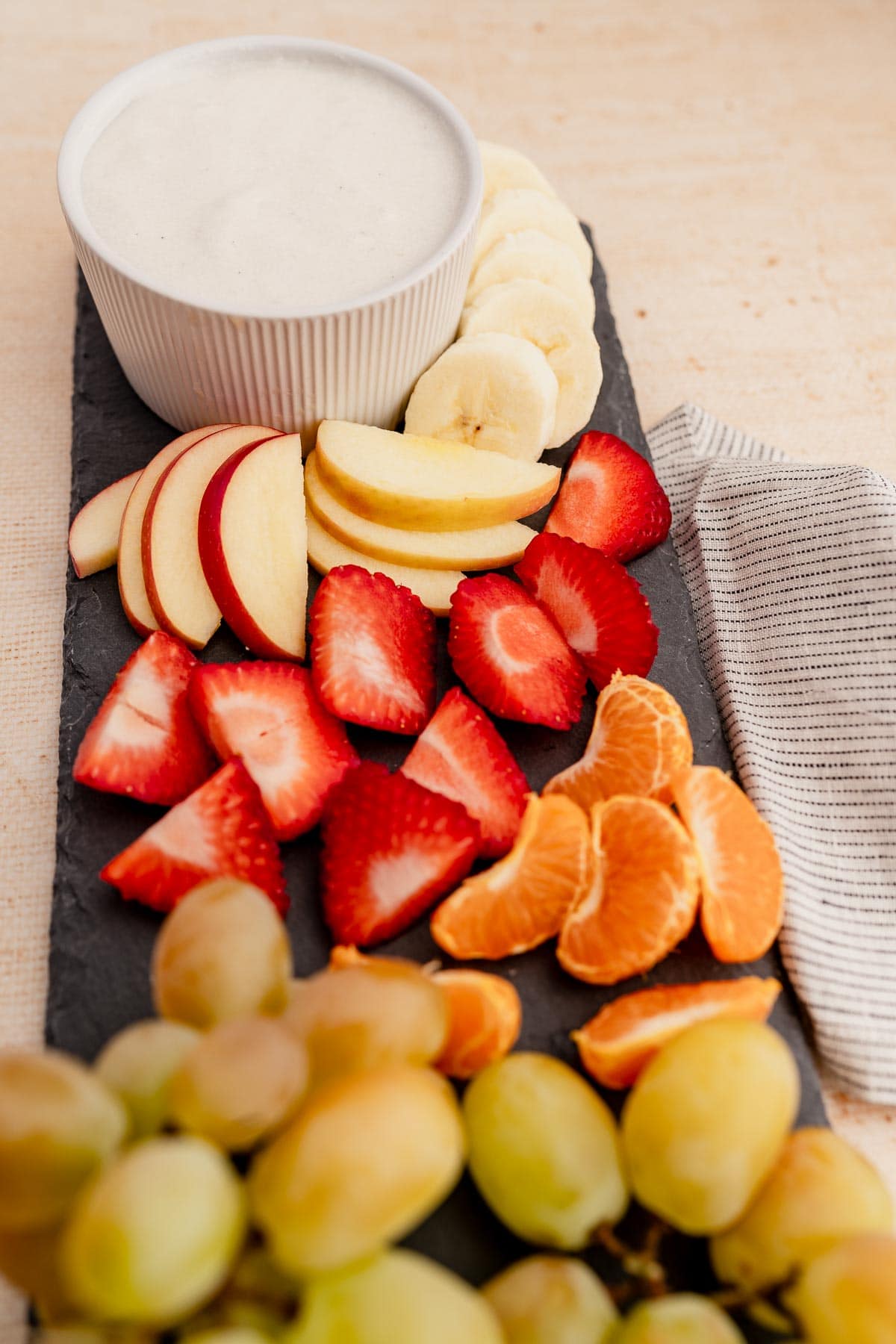 A platter with fruit, grapes, and a fruit dip.