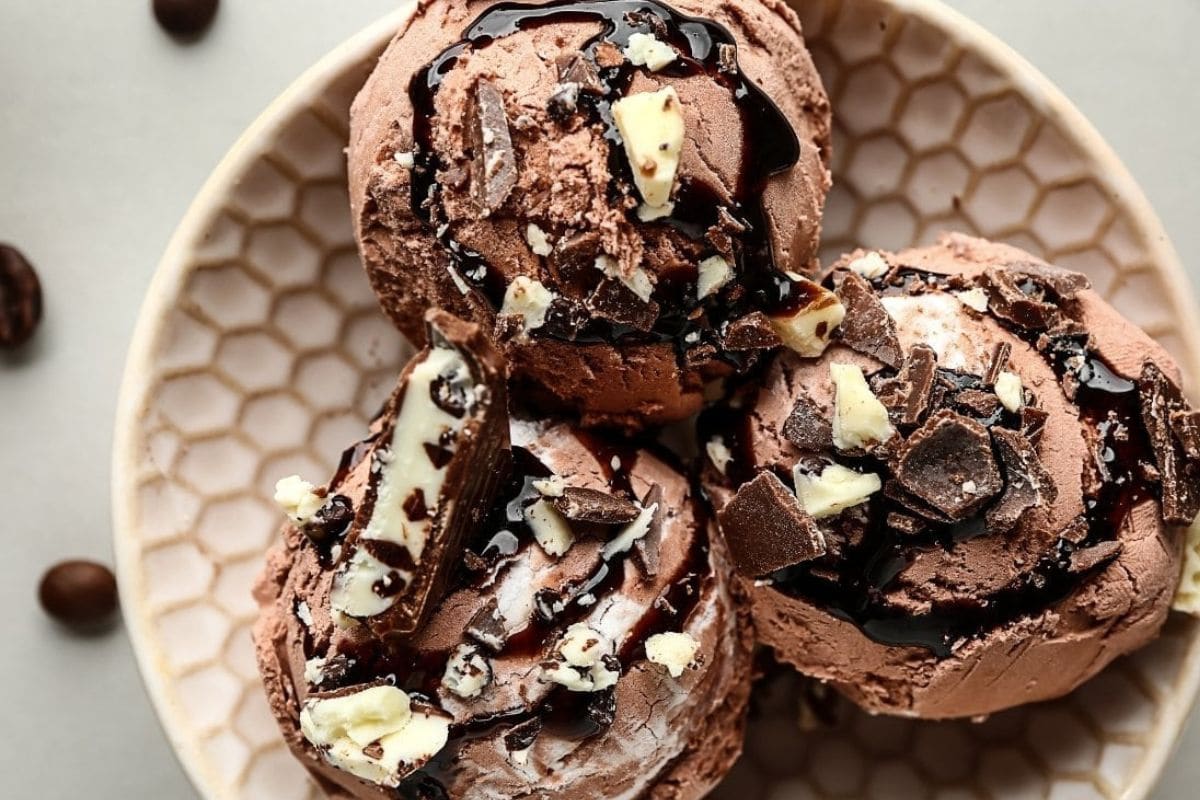 Three chocolate ice cream cones on a plate.