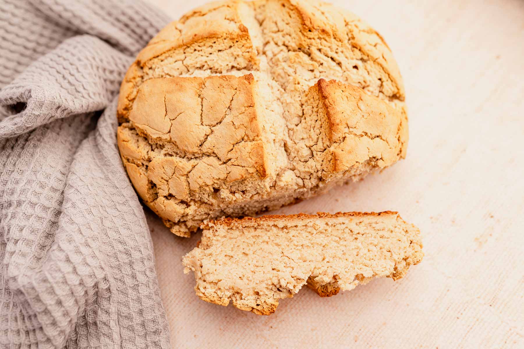 A gluten-free loaf of Irish soda bread with a piece missing.