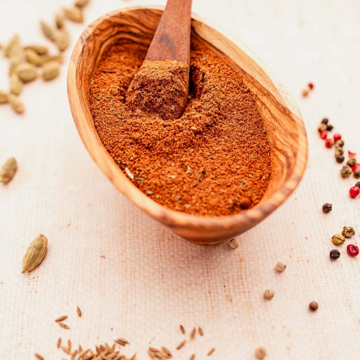 A shallow wooden bowl filled with Baharat Spice.