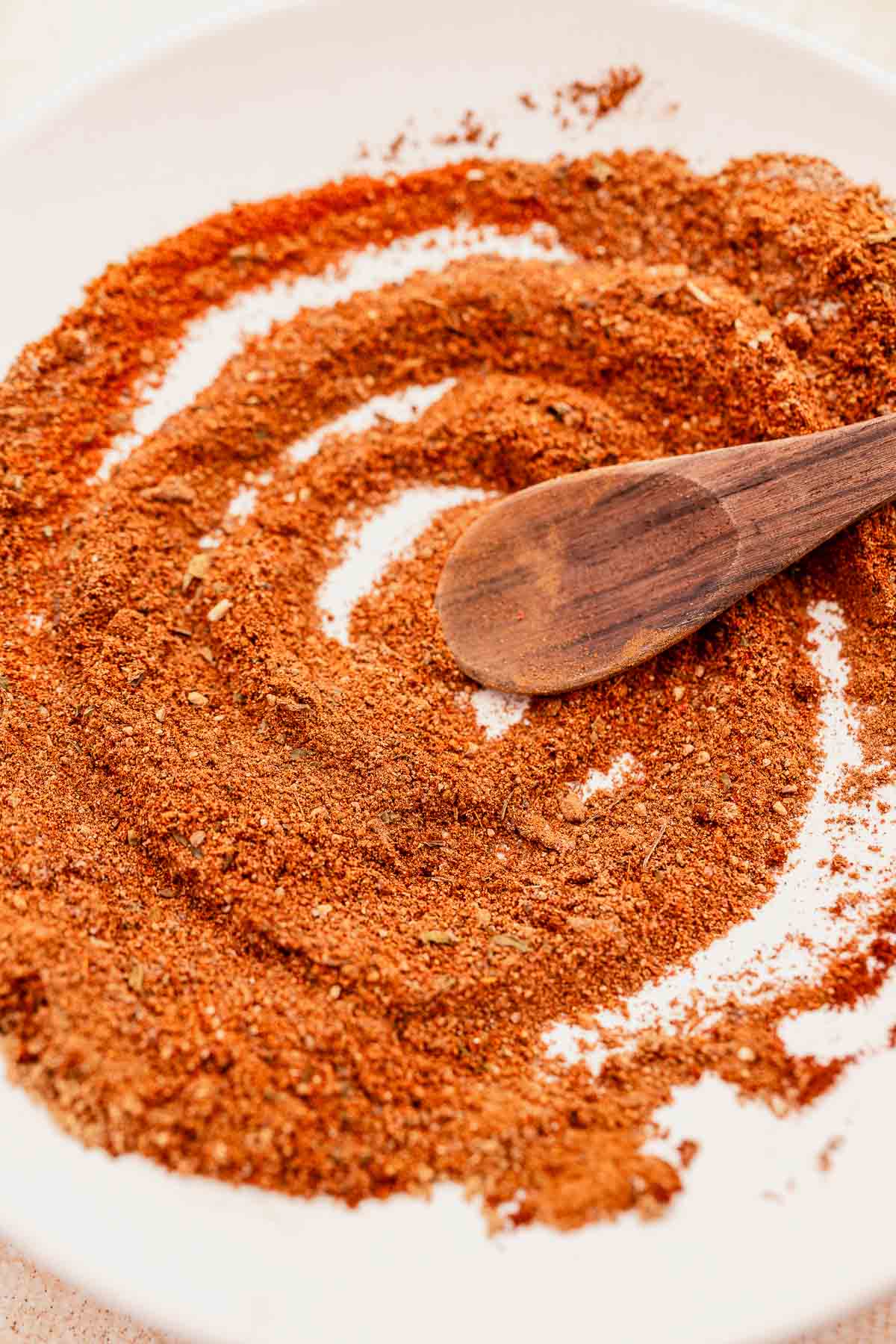 A bowl of Baharat Spice with a dark wooden spoon.