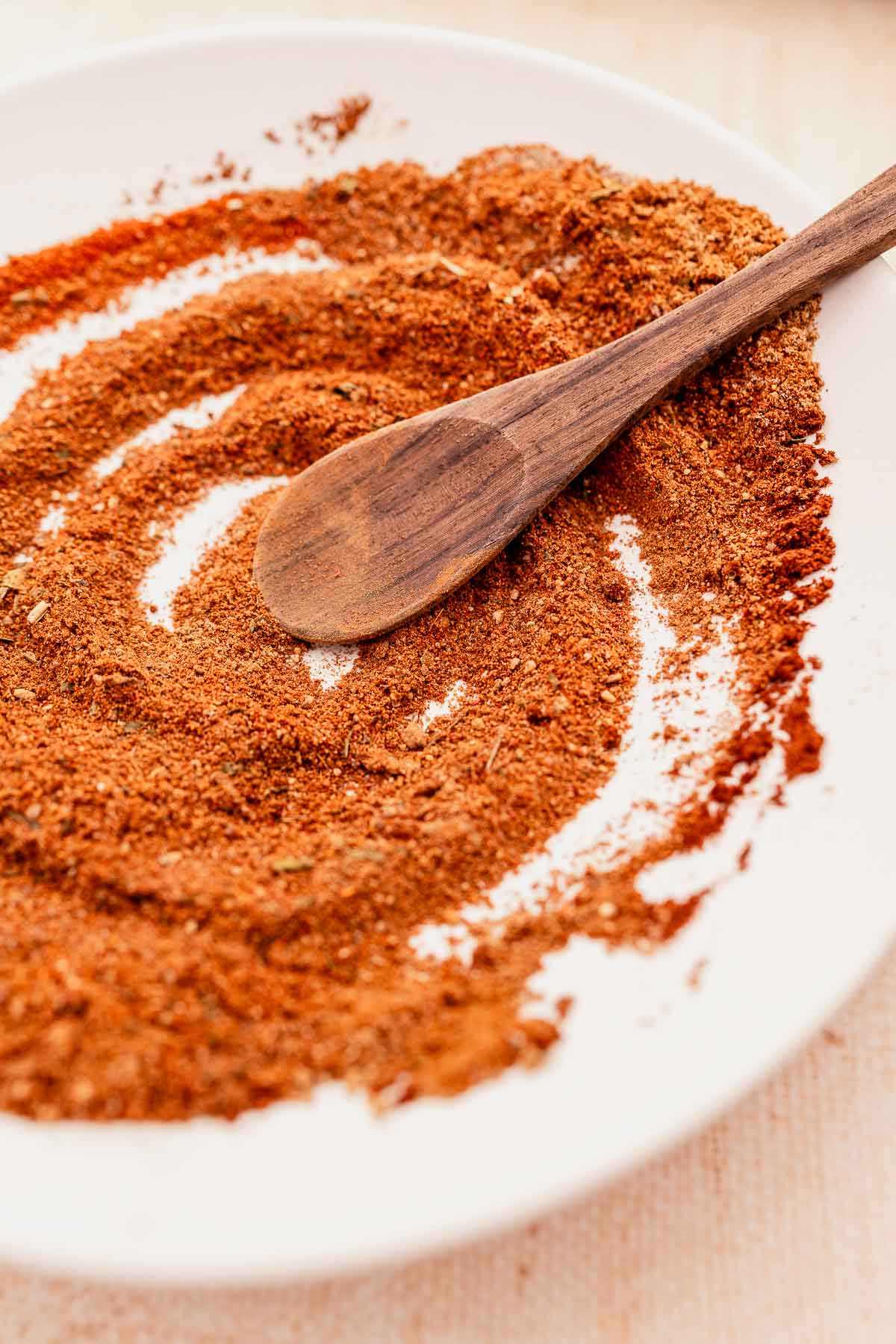 Baharat Spice in a white bowl with a dark wooden spoon.