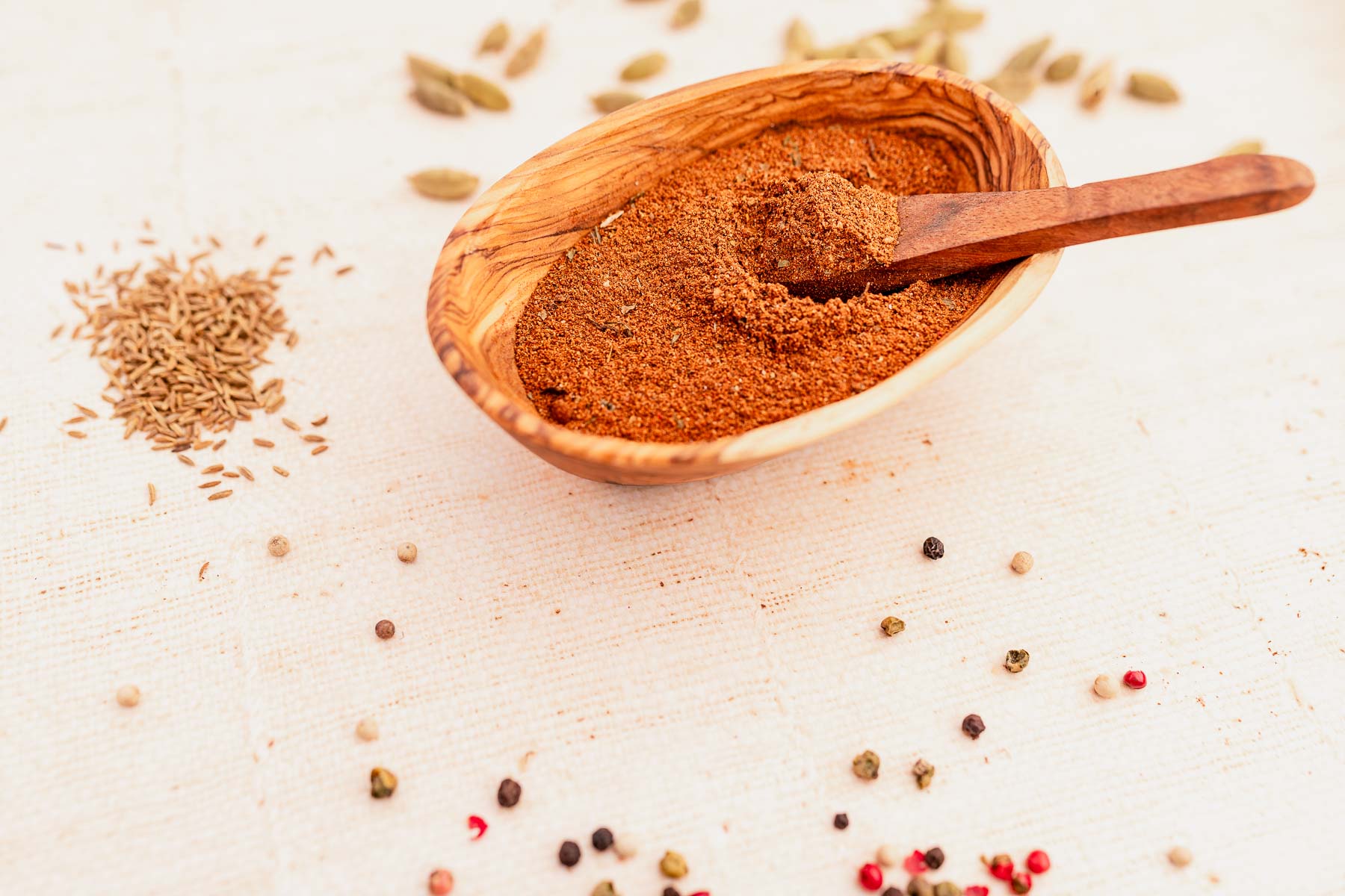 Baharat spices in a wooden bowl with a wooden spoon.