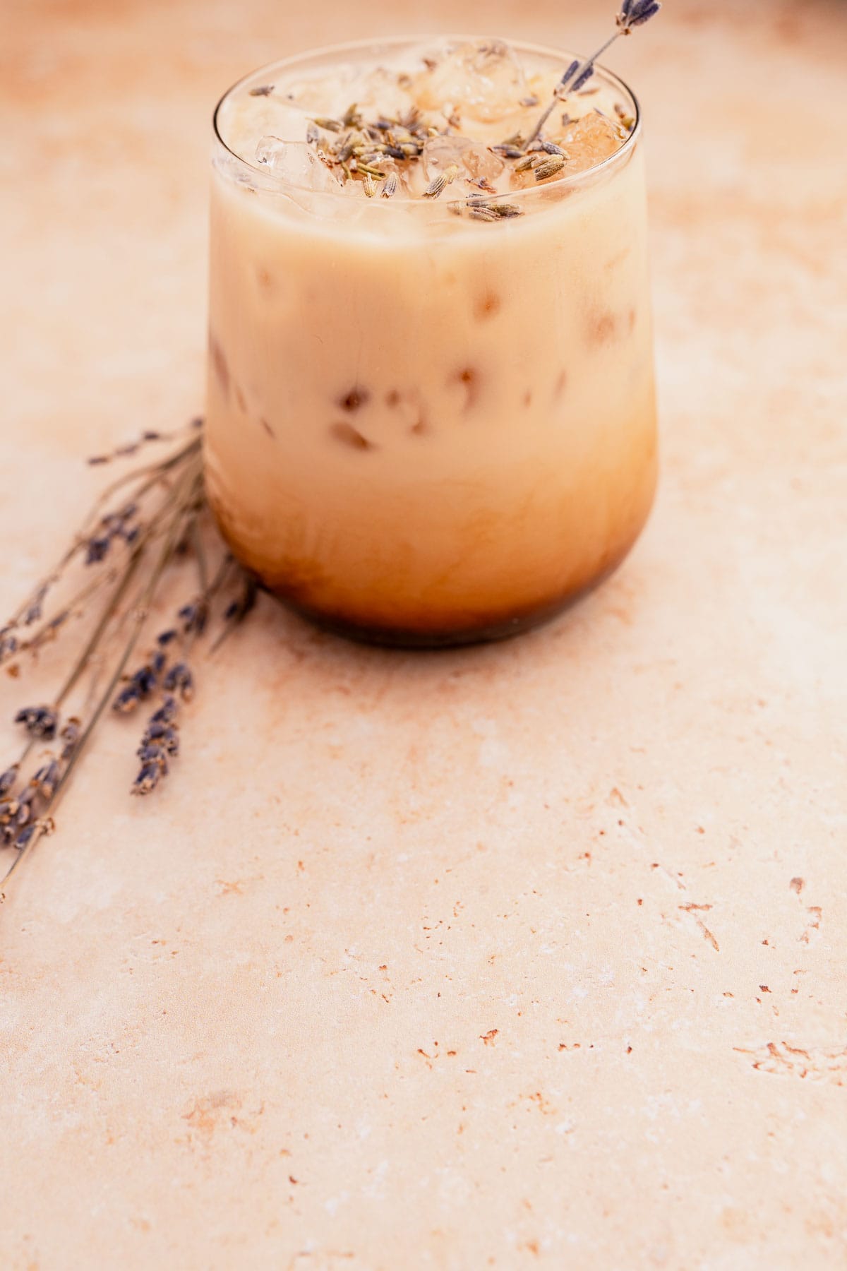 Iced lavender oatmilk latte on a marble surface.