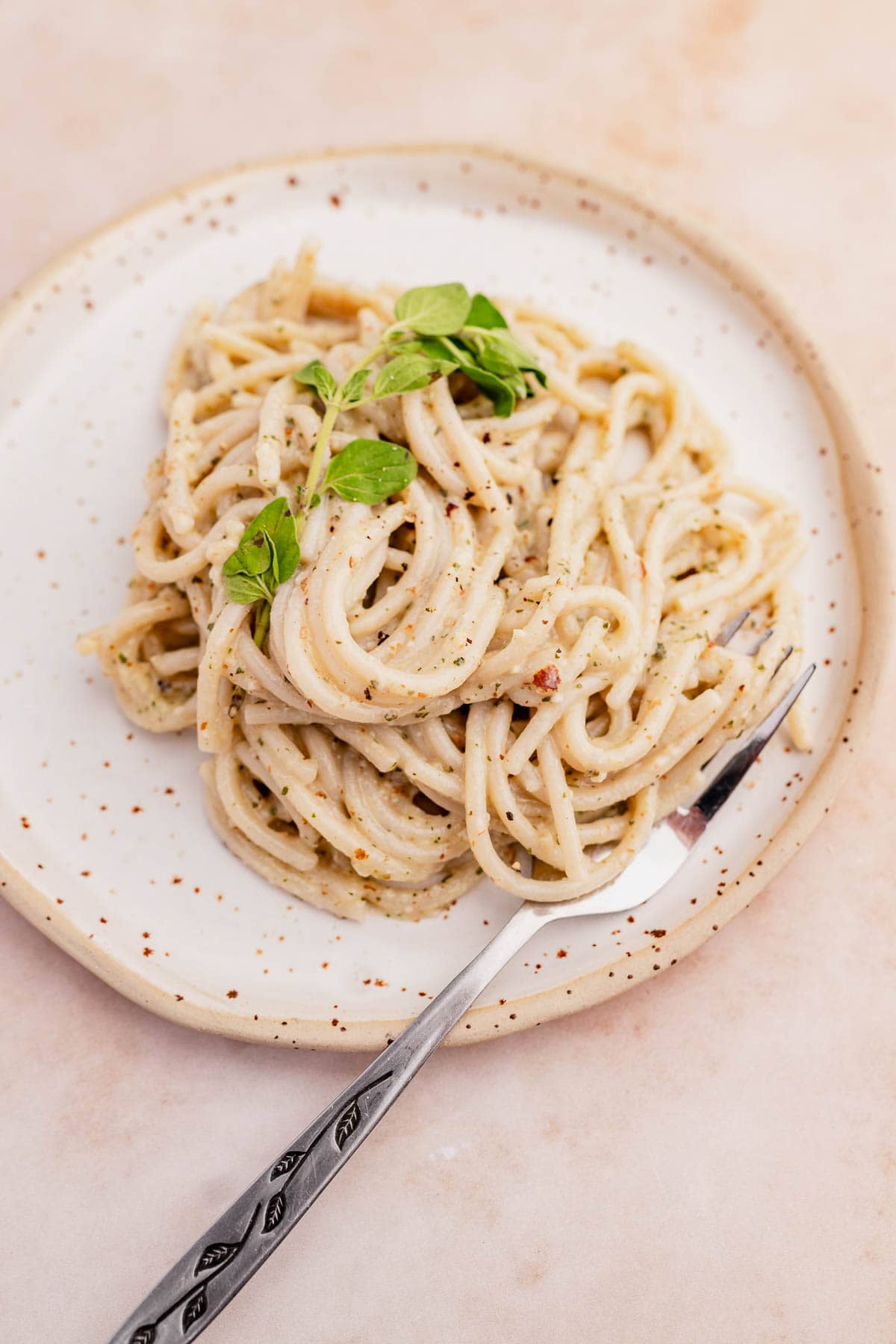A fork stuck in a creamy oregano pasta.