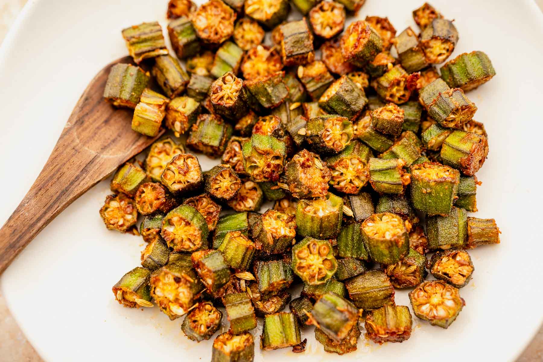 Sautéed chopped okra recipe in a dish with a wooden spoon.