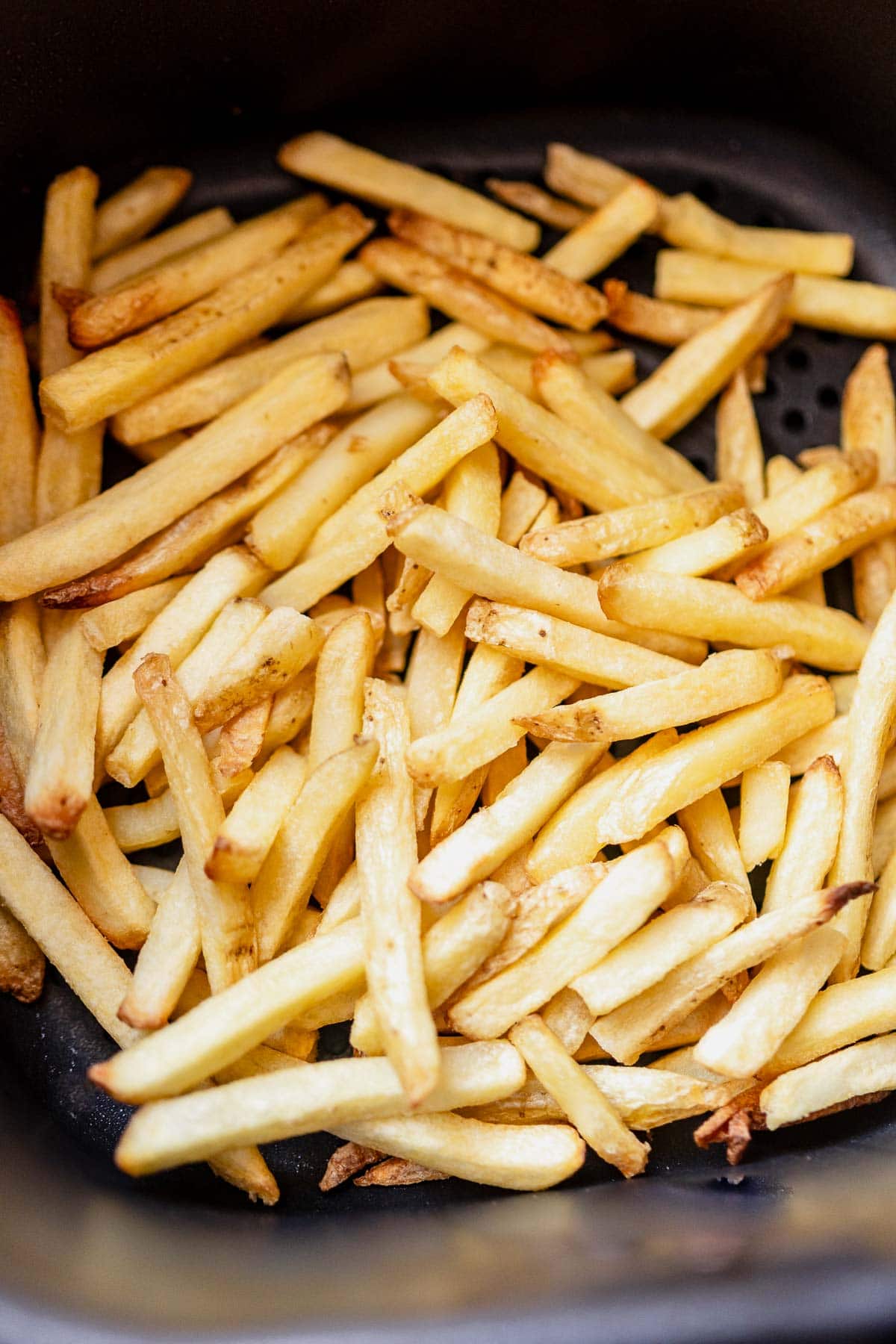A basket of freshly cooked frozen french fries in an air fryer.