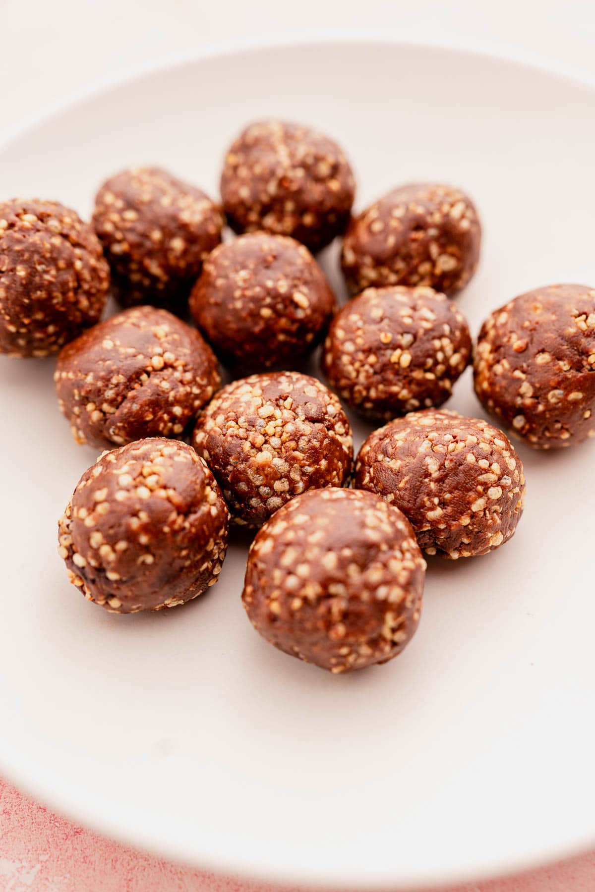 A close-up image of chocolate quinoa crunch bites arranged on a light pink plate.