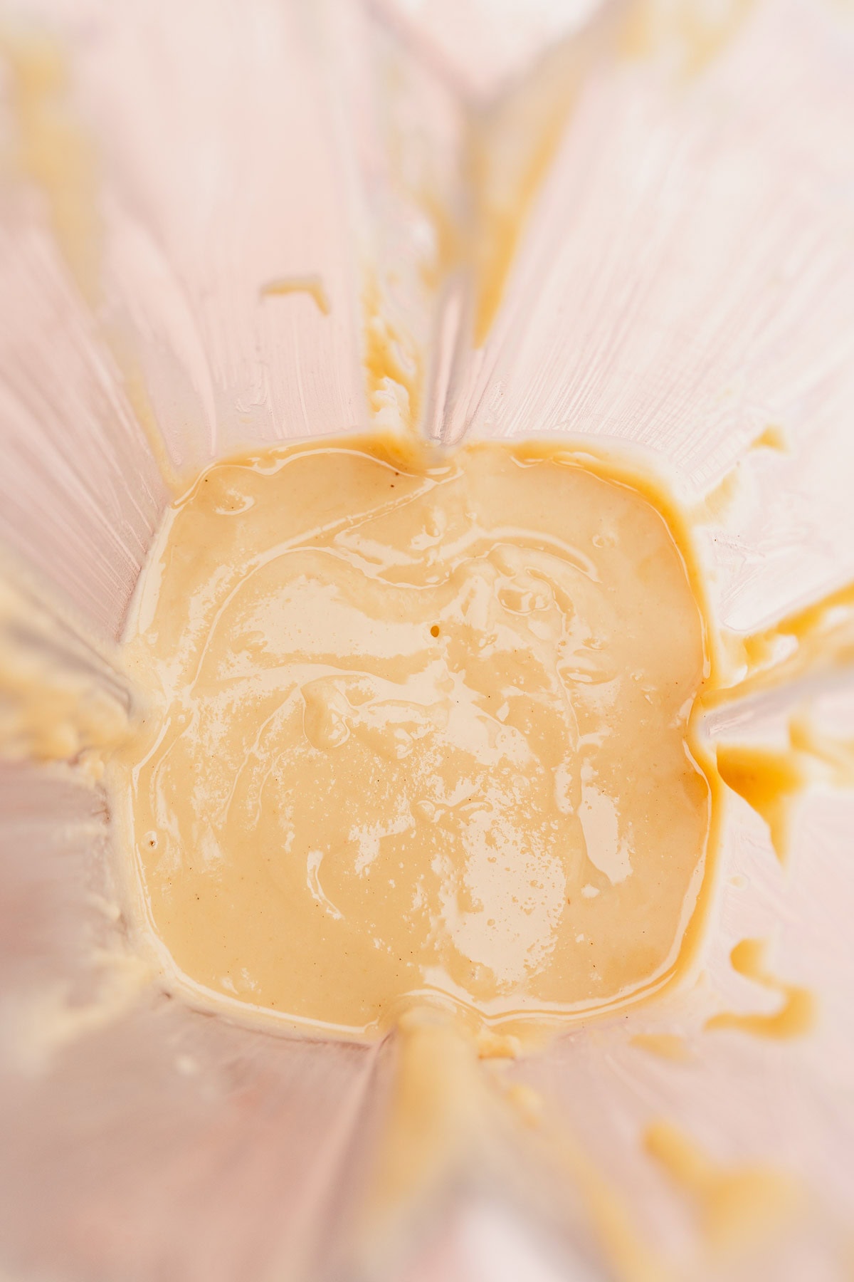 Close-up image of creamy macadamia nut butter in a jar with residue on the sides.