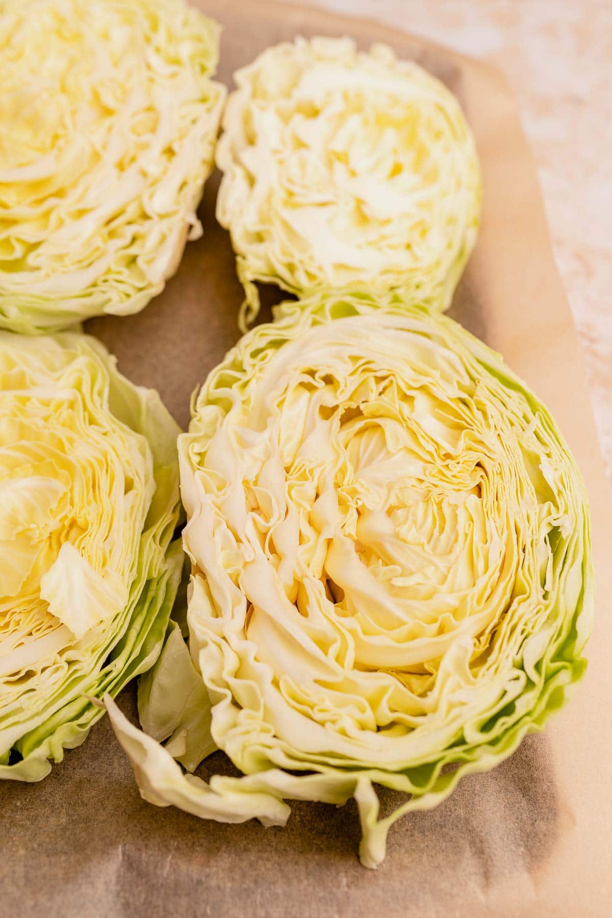 Halved cabbage steaks on a cutting board showing their intricate layers and textures, with focus on the crisp, fresh details of the cut surfaces.