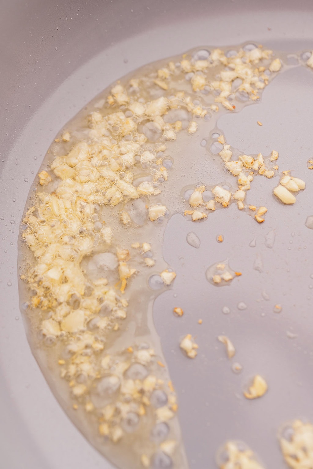 Chopped garlic sizzling in hot oil in a frying pan sets the perfect base for delicious garlic fried rice.