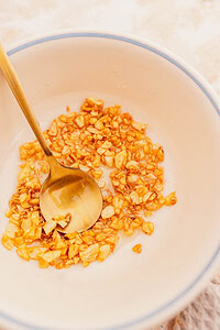 A bowl with chopped fried garlic and a golden spoon inside it sits next to a plate of aromatic garlic fried rice.