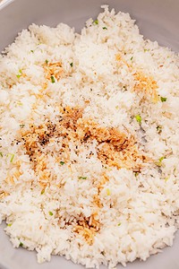 A plate of garlic fried rice seasoned with black pepper and soy sauce, garnished with chopped green onions.