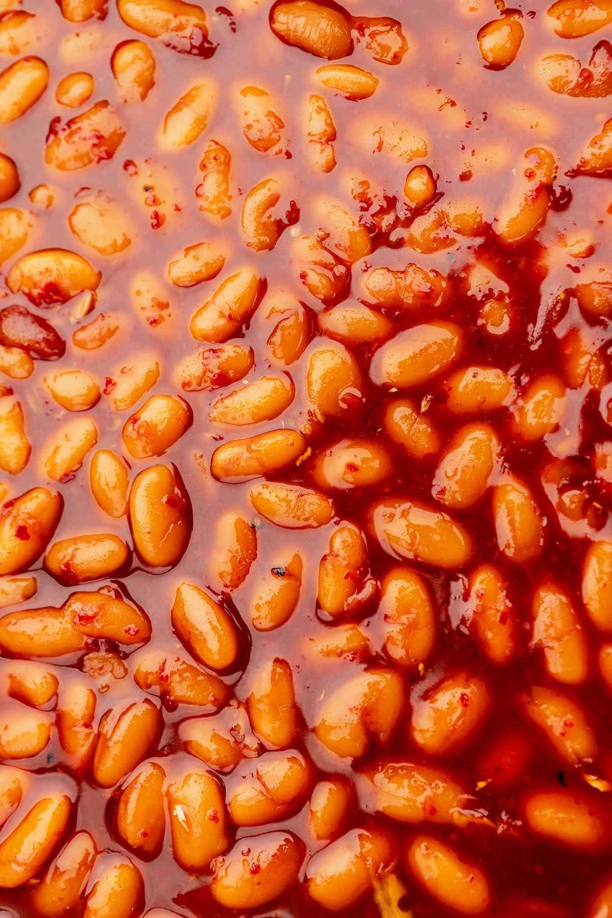 Close-up of Korean BBQ baked beans in a rich, reddish sauce.