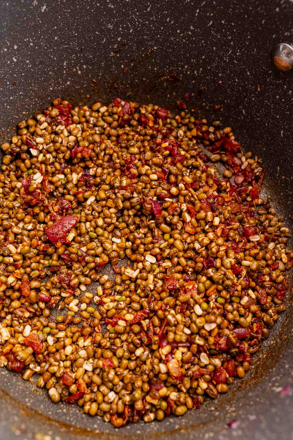 Sauteed mung beans, spices, and onions in a large pan.