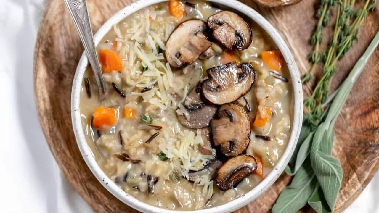 Wild rice and mushroom soup in a white bowl with sprigs of sage.
