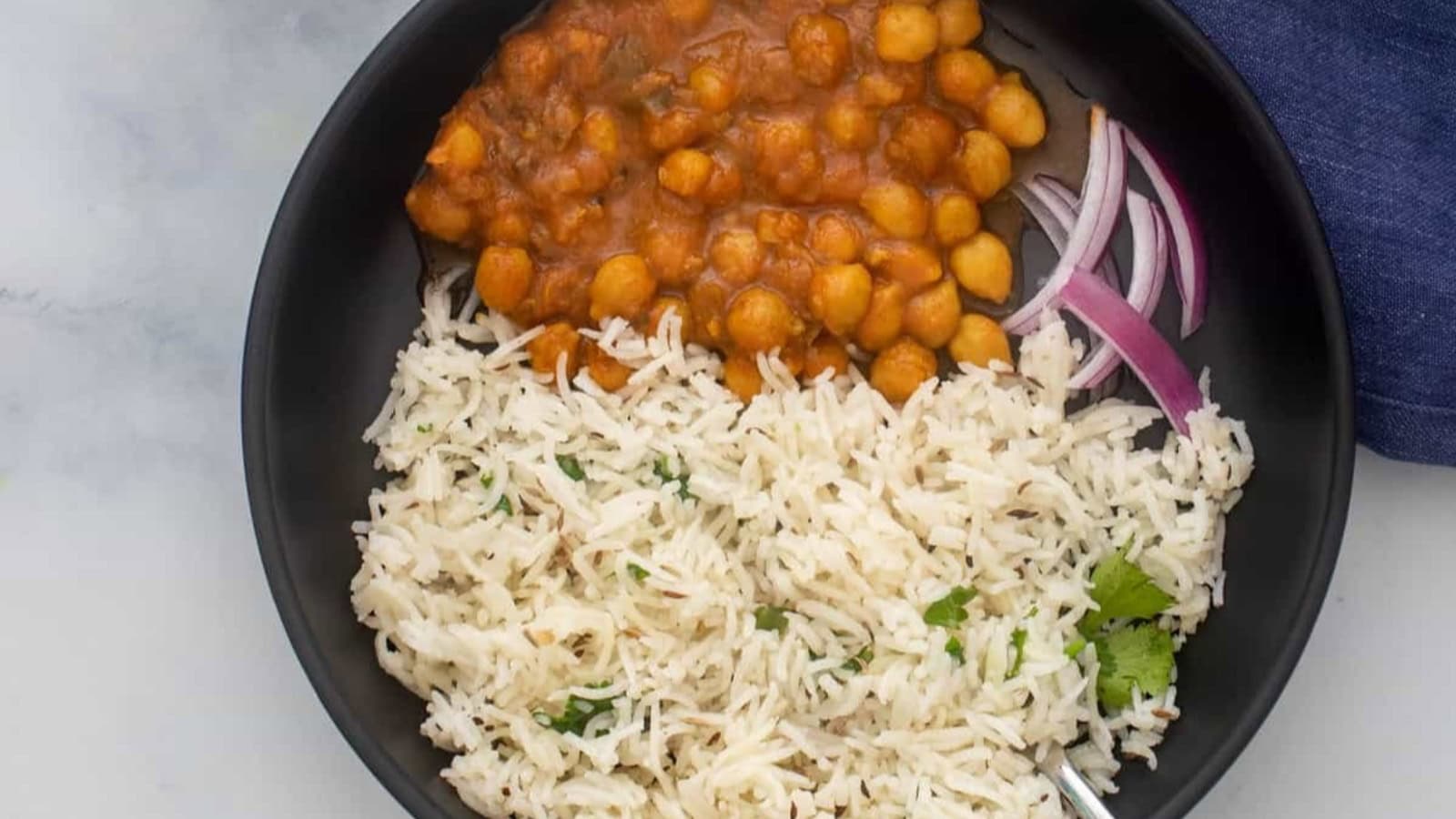 A straight view of cooked jeera rice in a white plate.