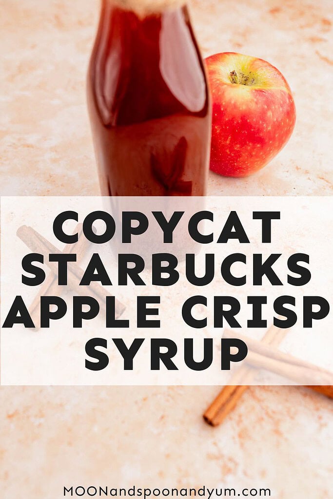 A bottle of apple syrup next to a whole apple and cinnamon sticks. Text reads "Copycat Starbucks Apple Crisp Syrup.