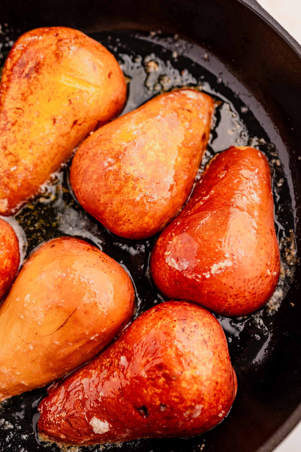 Caramelized pears in a black skillet, glistening with a rich chocolate balsamic glaze.