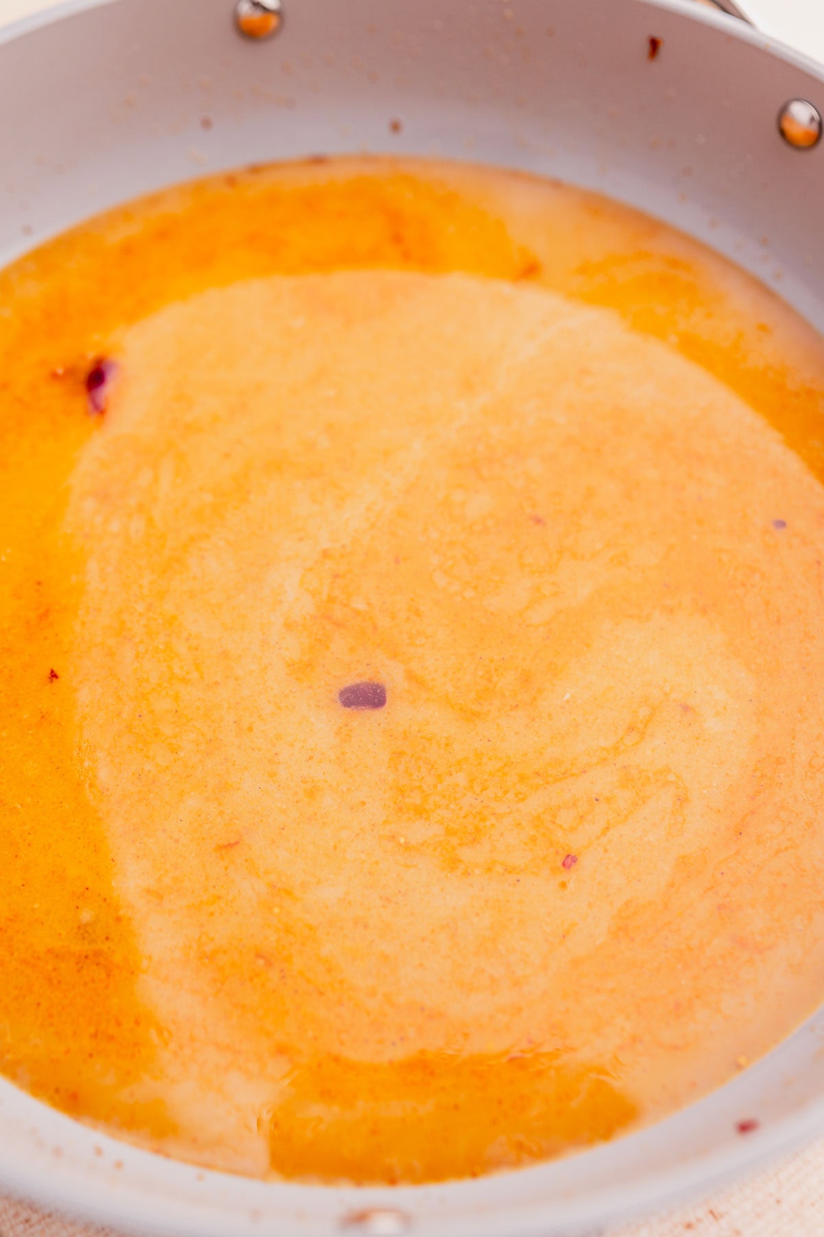 Simmering coconut milk and spices in a pot.