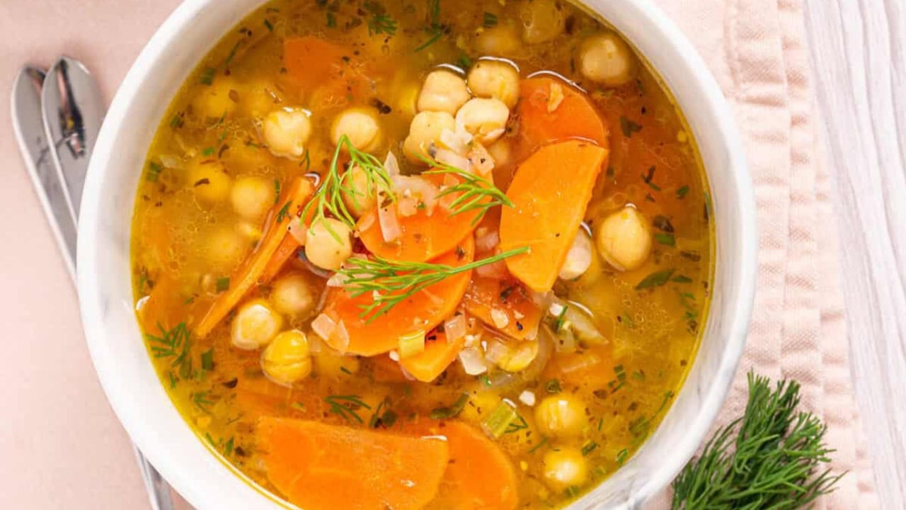An image of greek chickpea soup in a bowl with utensils beside it.