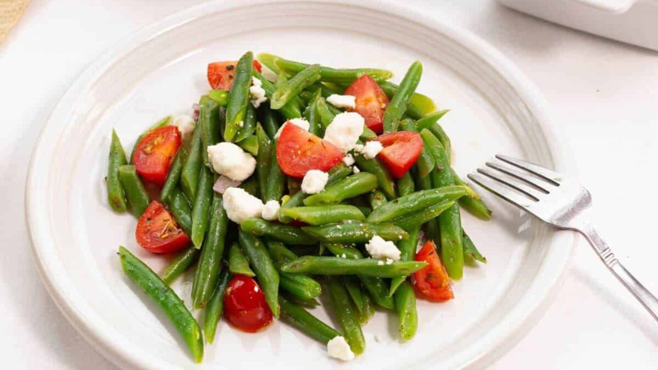 Green beans and tomatoes on a white plate.
