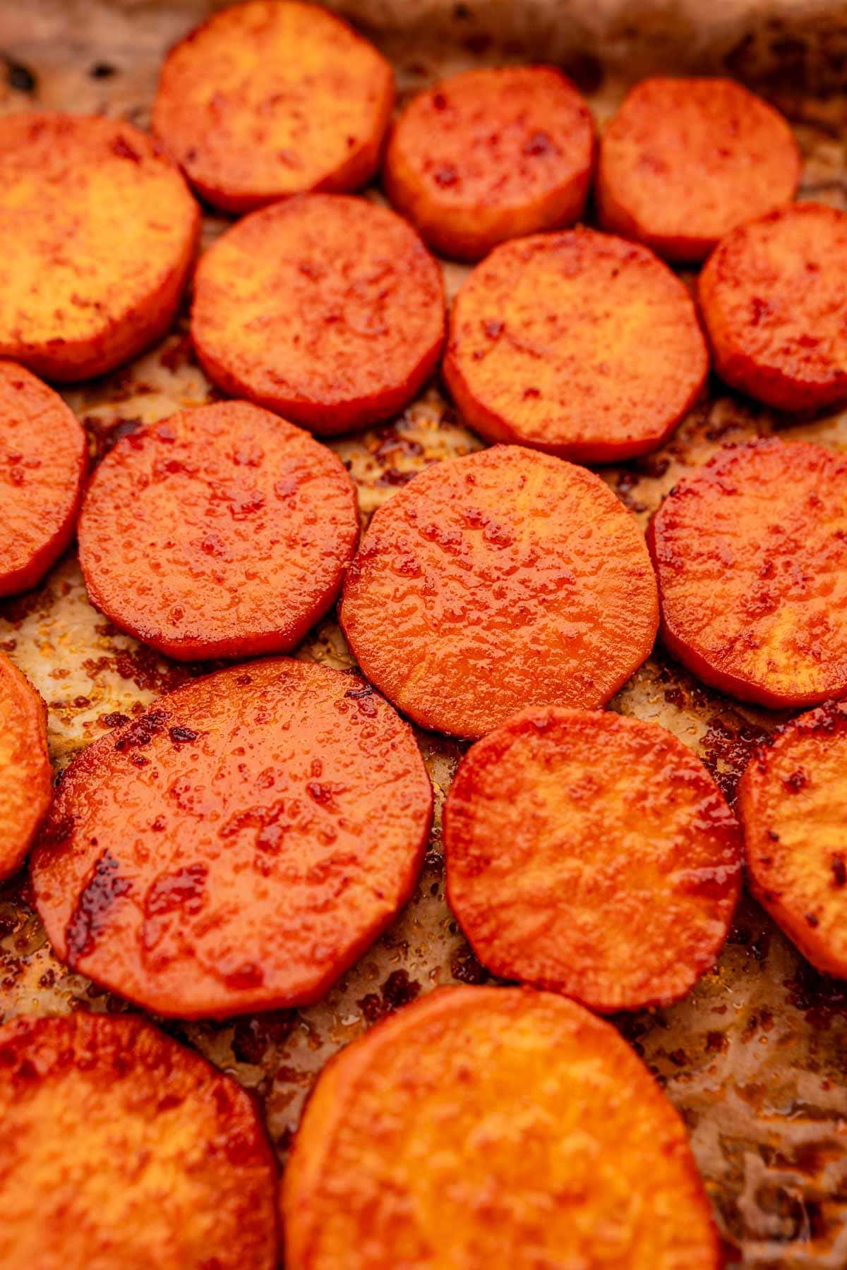 Baked sweet potato slices are perfectly seasoned and roasted to golden perfection on a baking sheet.