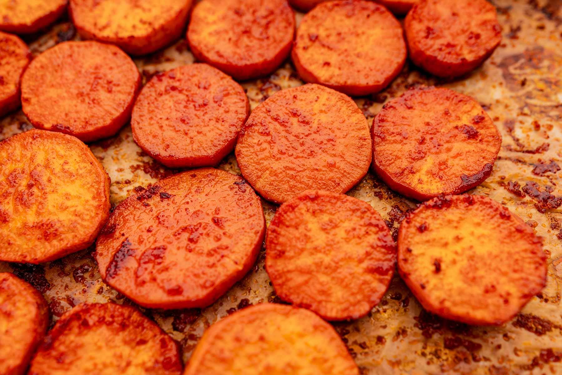 Baked sweet potato slices rest perfectly on a baking sheet, their roasted flavor and golden edges inviting you to indulge.