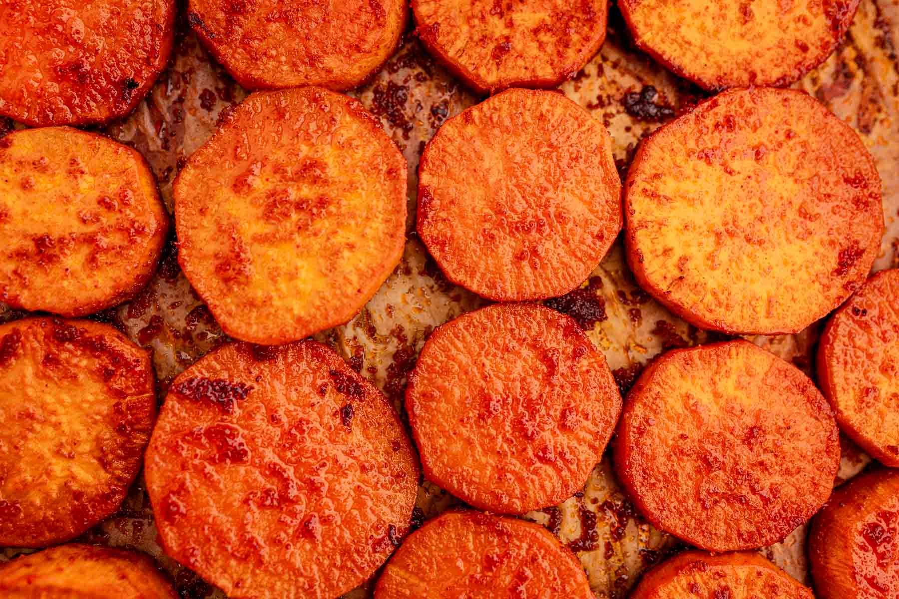 Close-up of baked sweet potato slices perfectly arranged on a baking sheet.