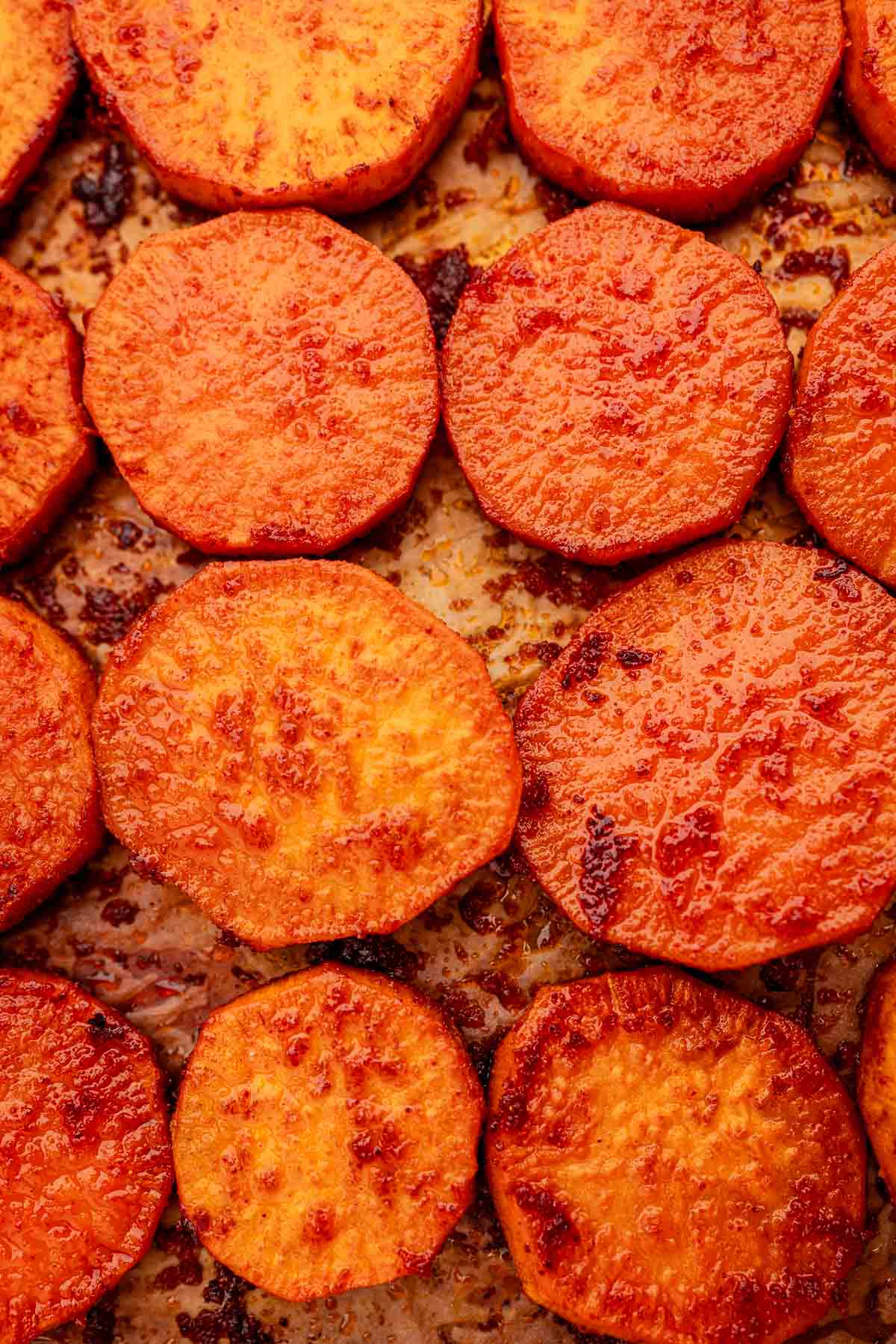 Close-up of baked sweet potato slices on a baking sheet, showcasing their lightly caramelized, golden-brown surface.