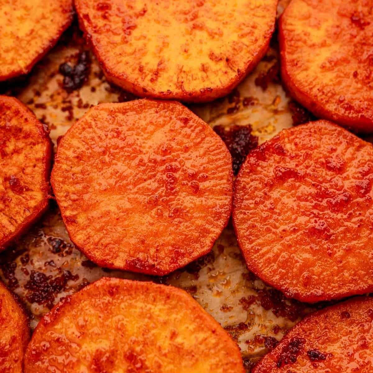 Close-up of baked sweet potato slices arranged perfectly on a baking sheet.