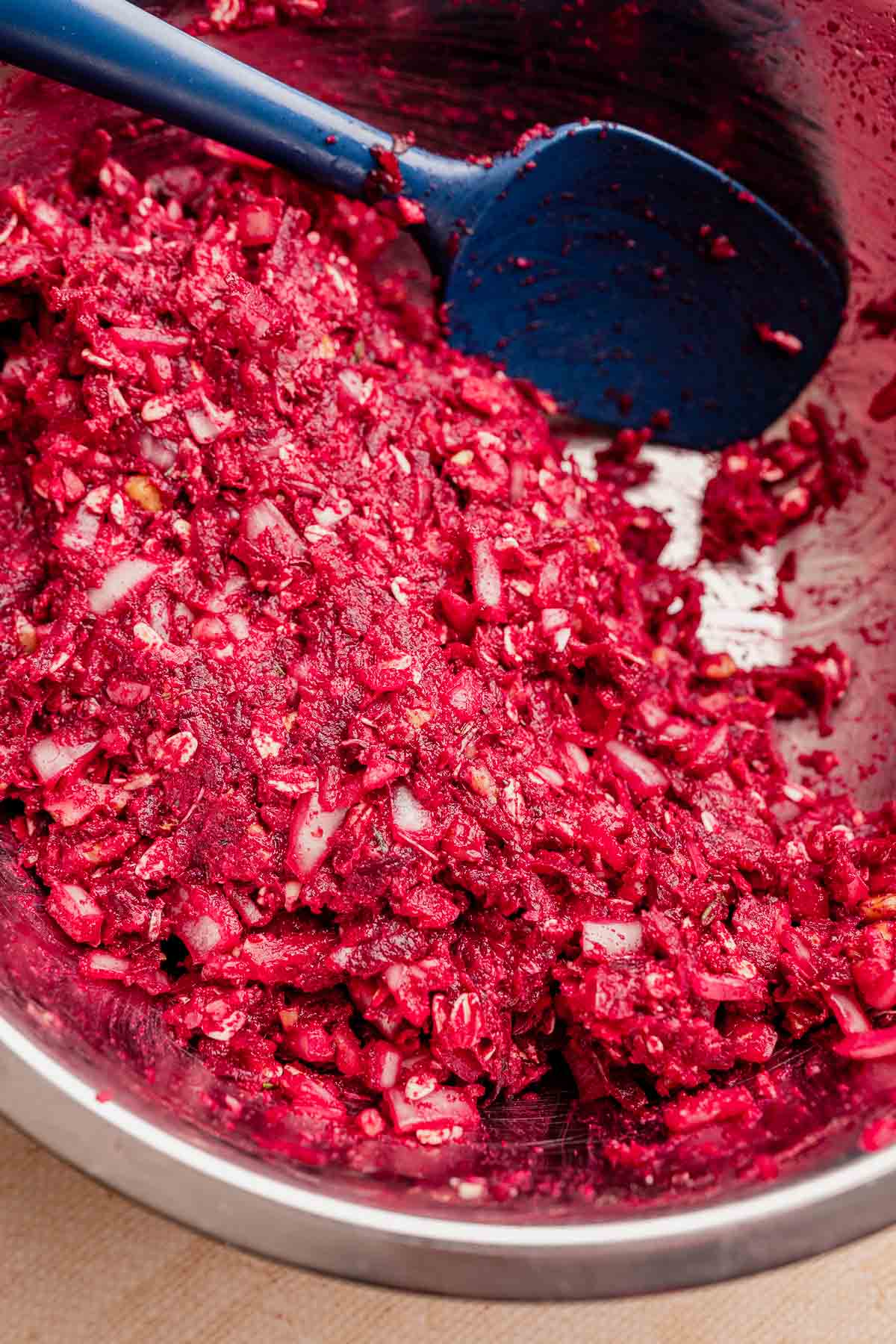 A bowl of vibrant red, finely chopped beet mixture with visible onions sits invitingly, perfectly complementing a hearty vegetarian roast. A blue spatula rests on the side, ready for serving.
