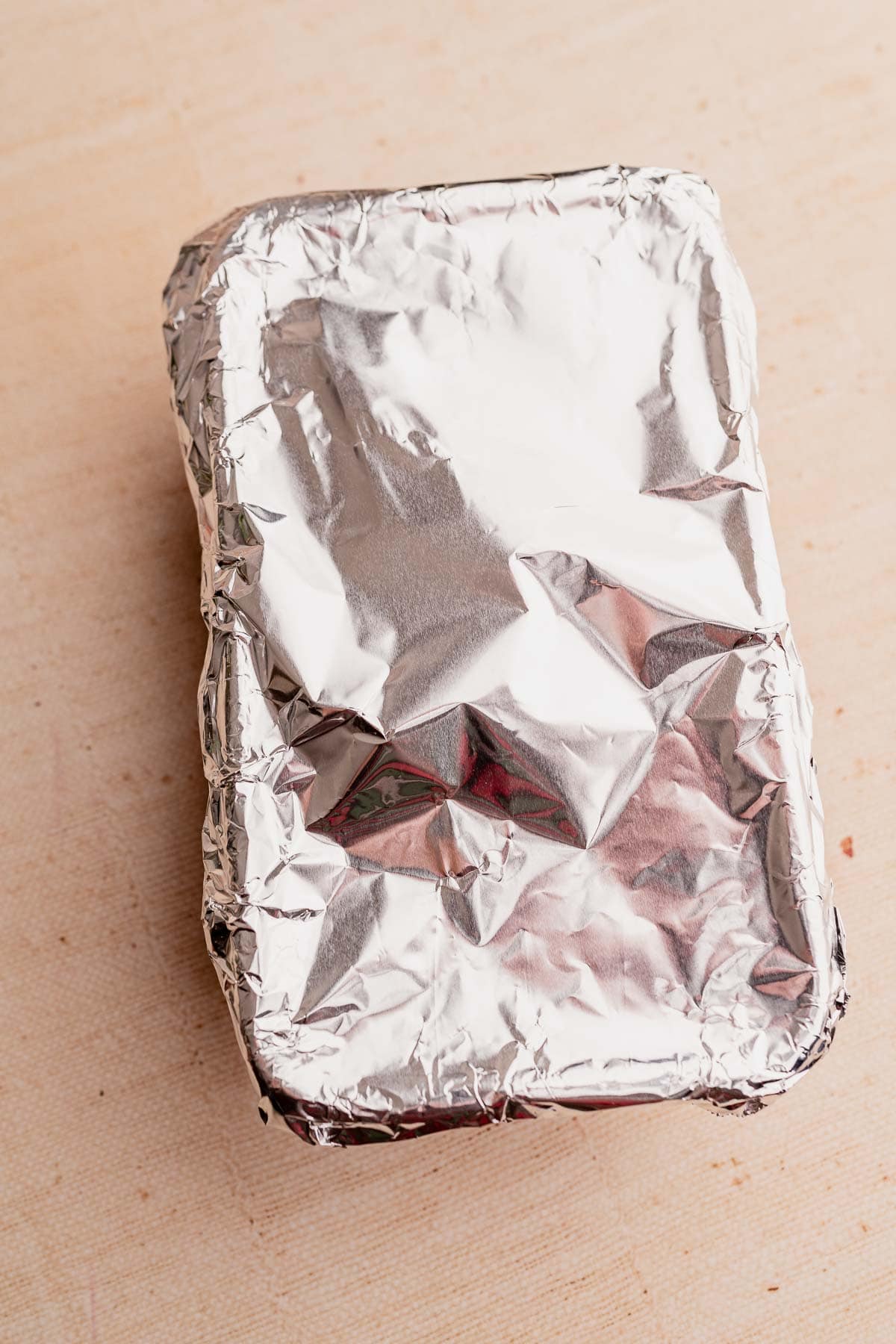 A rectangular foil-wrapped package sits on a light surface, hinting at the savory delights of a vegetarian roast within.