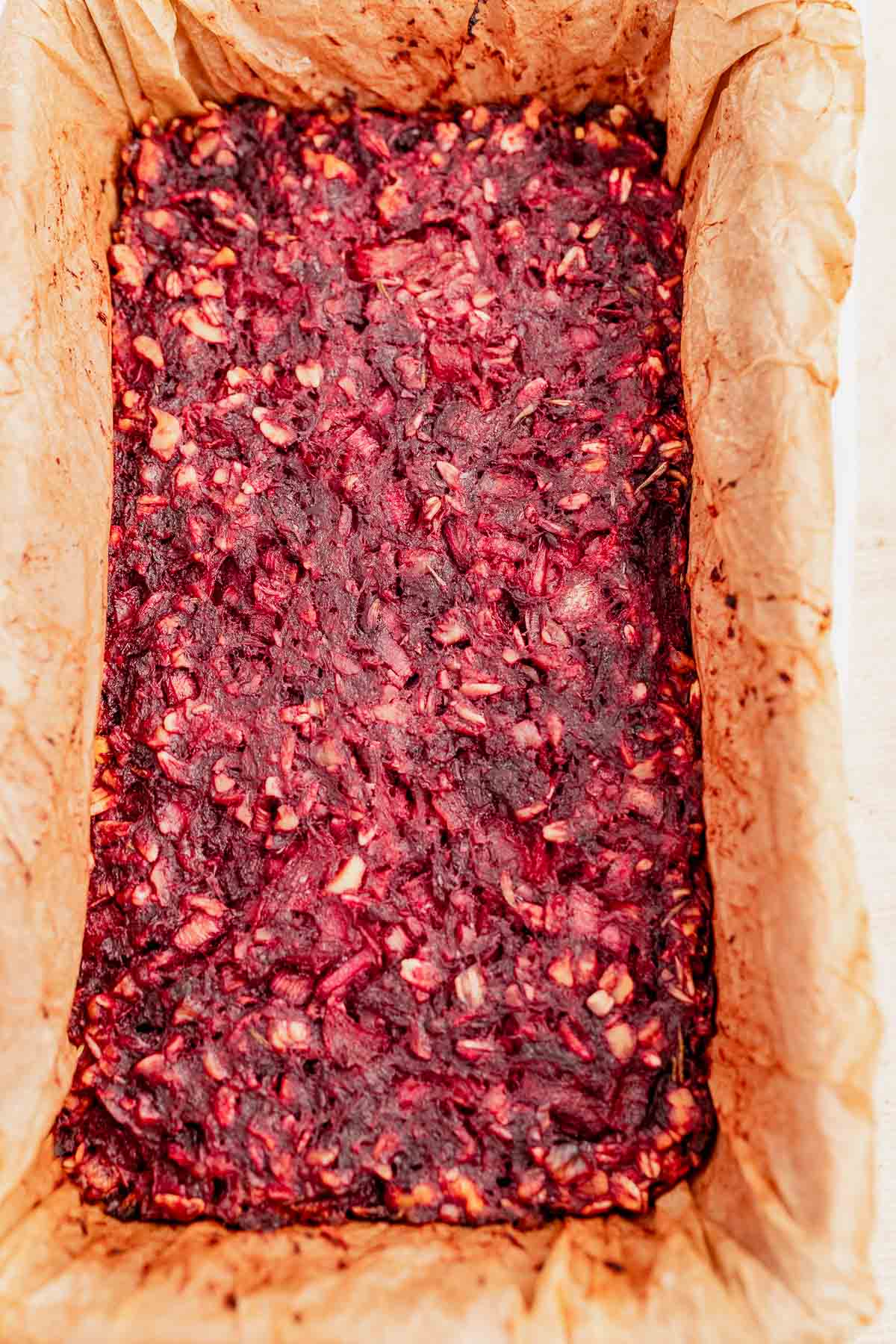 A rectangular loaf of dark red beetroot and nut mixture, baked in a parchment paper-lined pan, offers a delicious twist on a vegetarian roast.