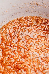 Close-up of a bubbling caramel sauce in a pan, showing its golden-brown color and glossy texture.