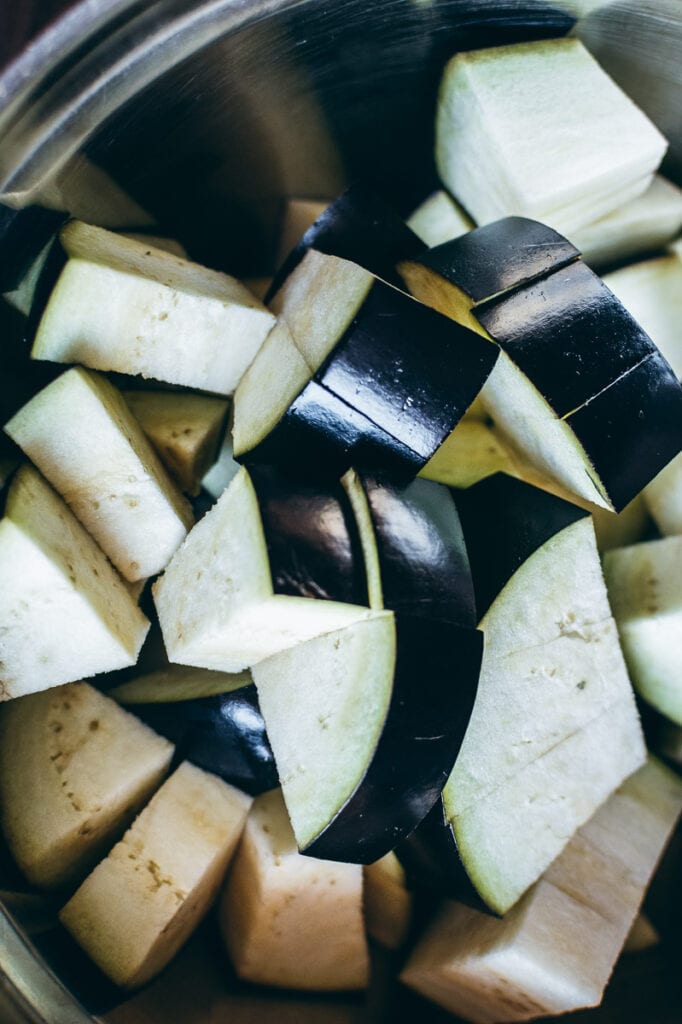 Chopped eggplant pieces rest in a metal bowl, showcasing their purple skin and pale flesh, perfectly prepped for the air fryer.