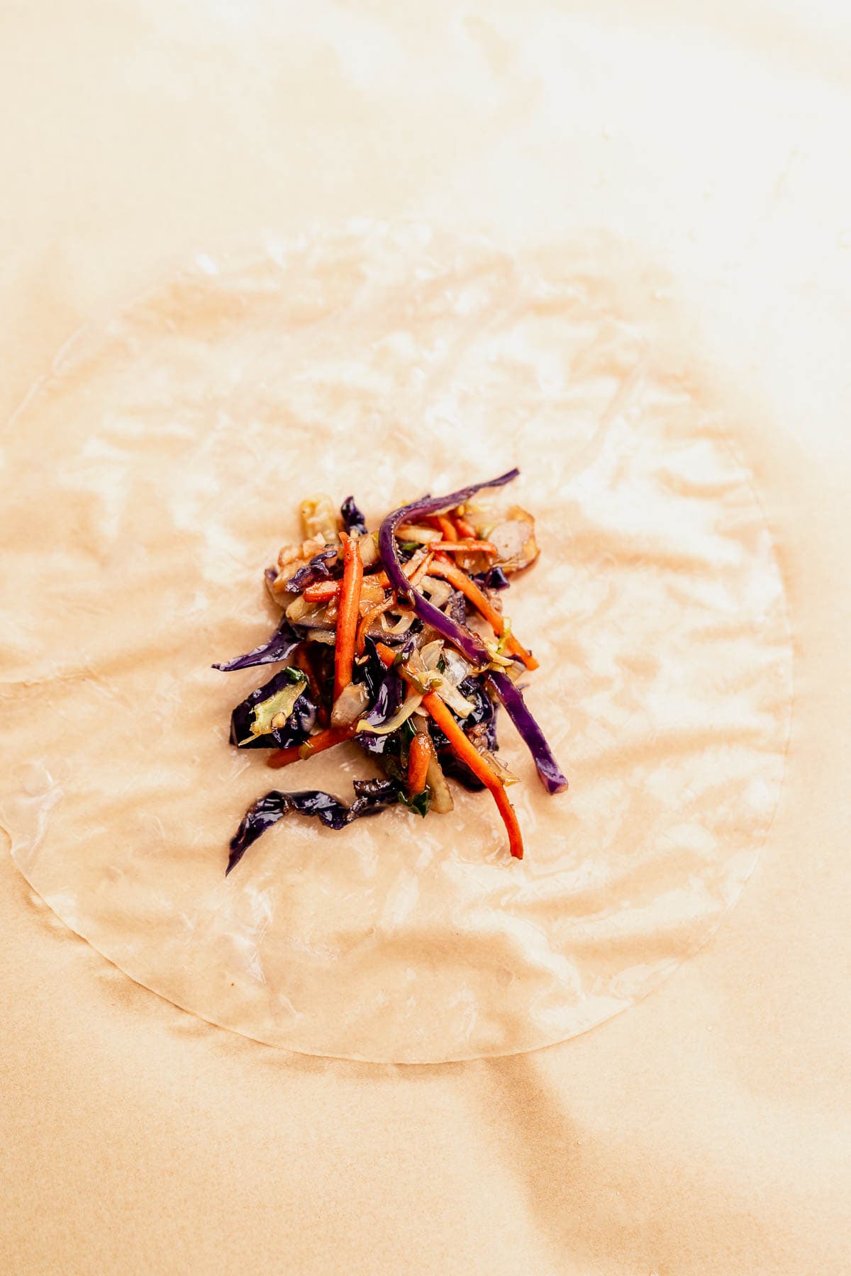Rice paper filled with sliced vegetables like red cabbage and carrots, neatly arranged in the center on a light surface, perfect for turning into crispy air fryer rice paper dumplings.