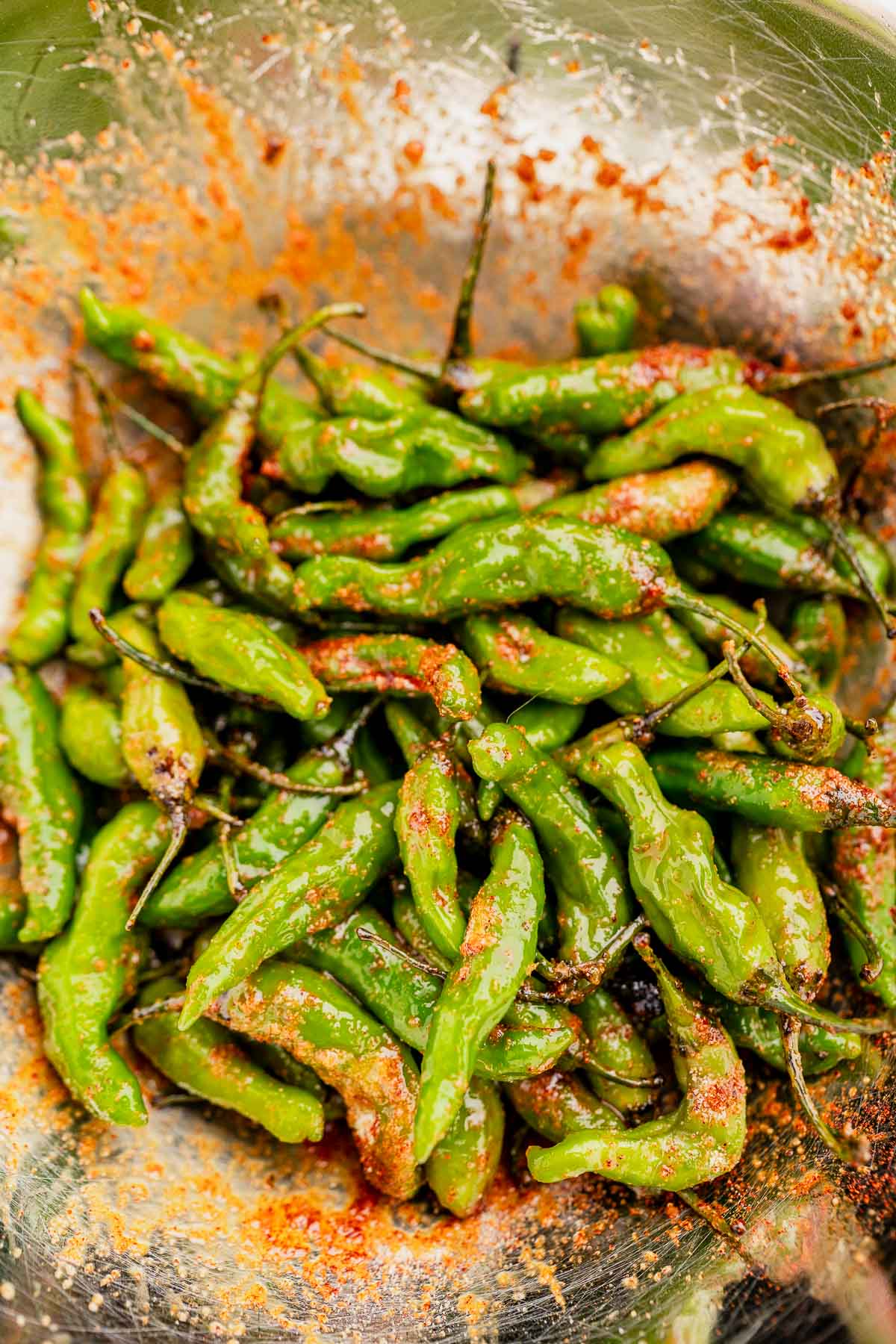 A bowl of air fryer shishito peppers, lightly charred and seasoned with spices and salt.