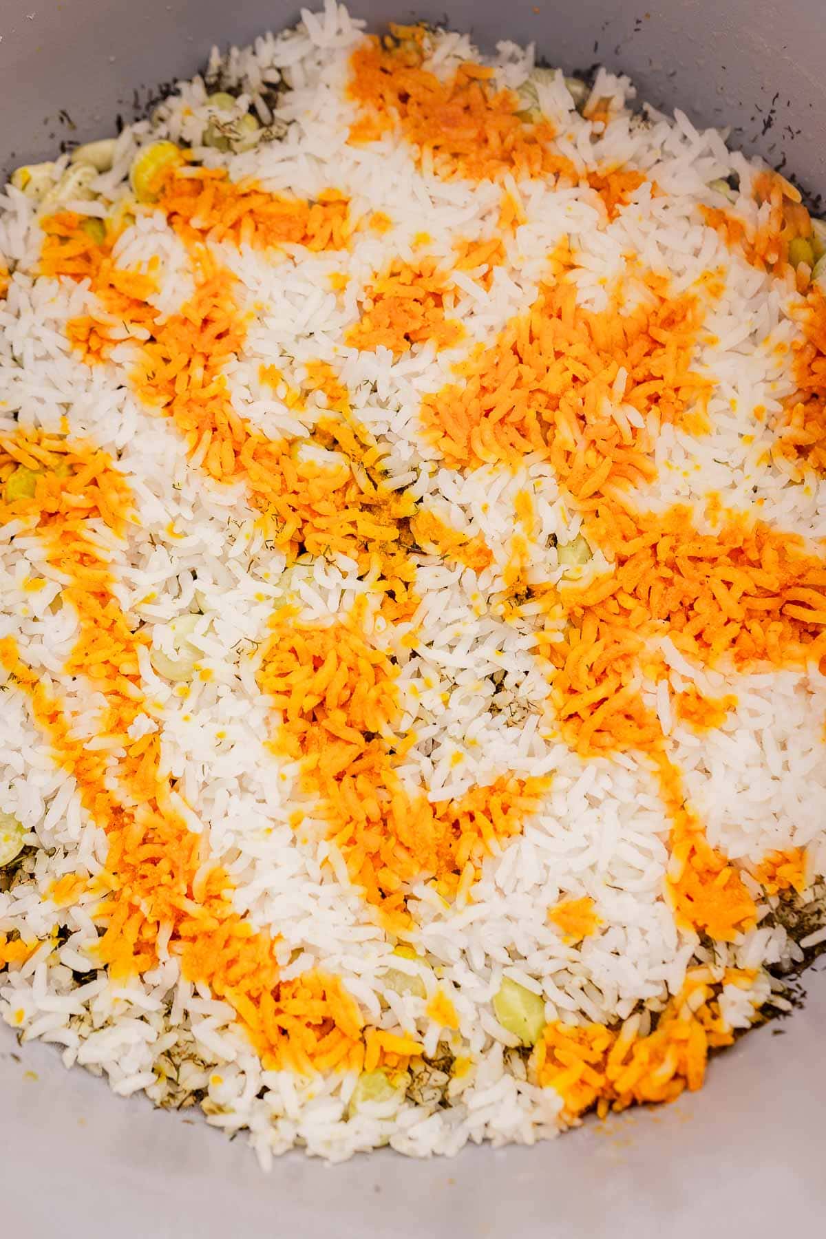 Cooked basmati rice with fragrant saffron on top, partially revealing a hint of dill and herbs mingling with tender beans underneath.