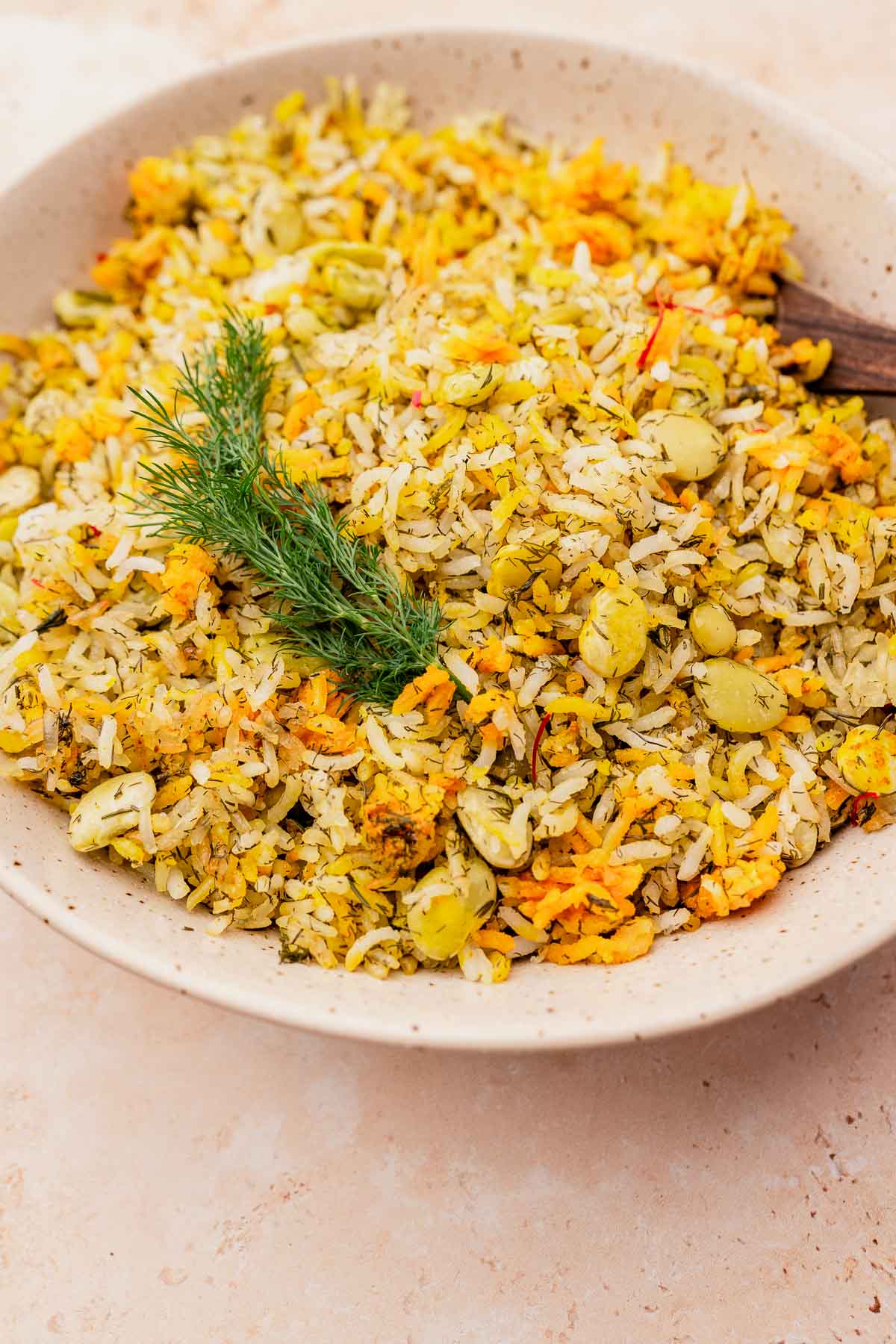 A bowl of dill rice mixed with fresh herbs and tender lima beans, beautifully garnished with a sprig of dill on a light background.