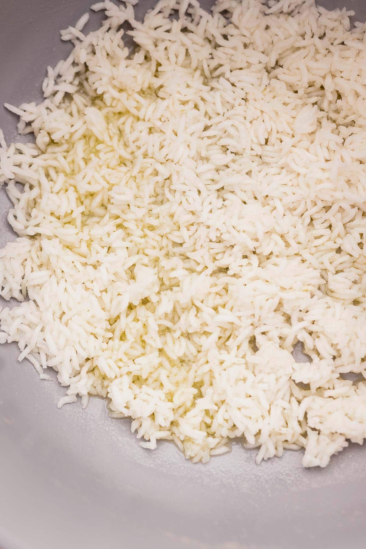 Cooked white rice, infused with the subtle fragrance of dill, is spread out on a flat surface.