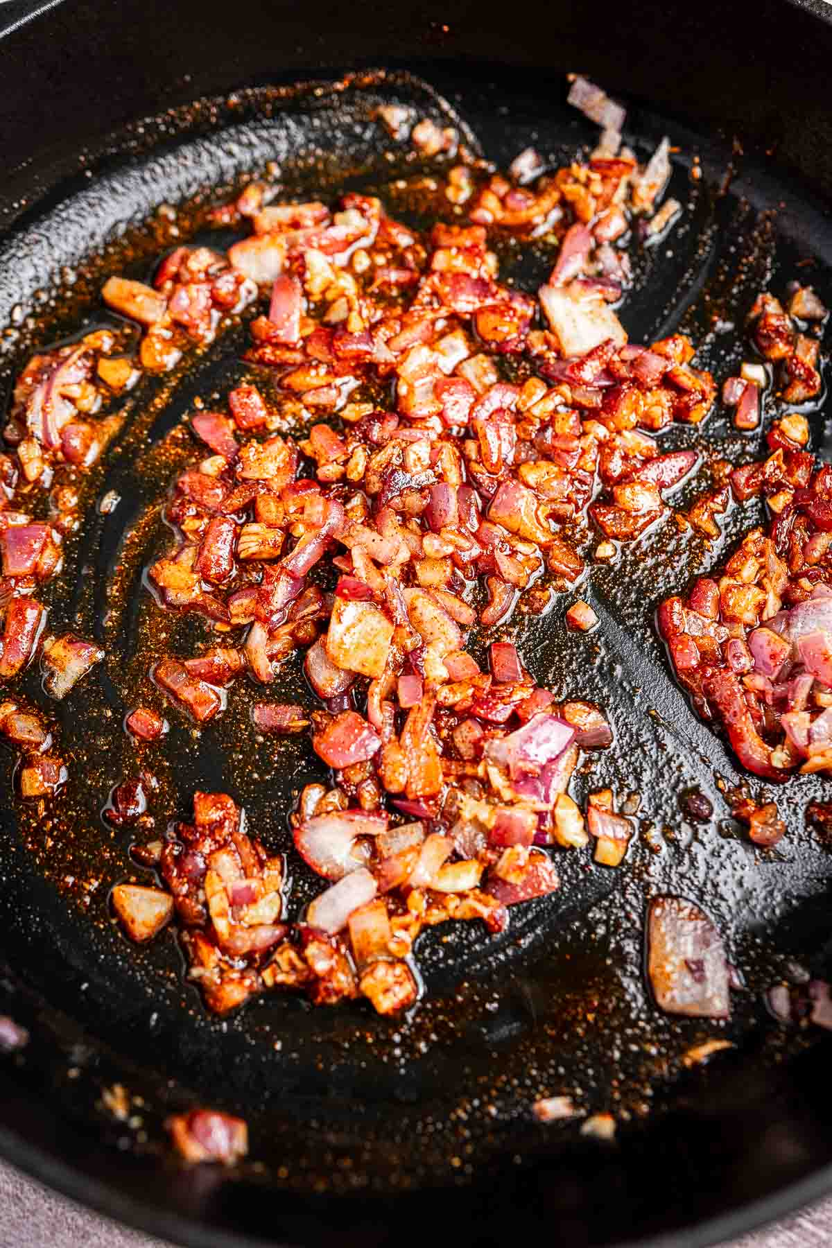 Chopped onions and garlic are sautéed in a black pan, browned and slightly caramelized, creating the perfect base for tender spinach and hearty chickpeas.