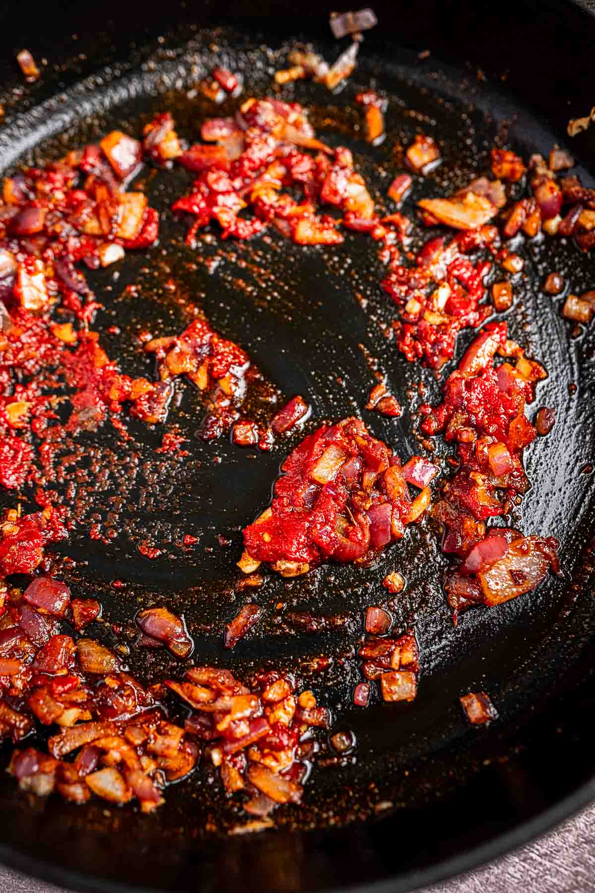 In a black pan, chopped onions and red paste are sautéed to perfection, enhanced with vibrant spinach and hearty chickpeas.