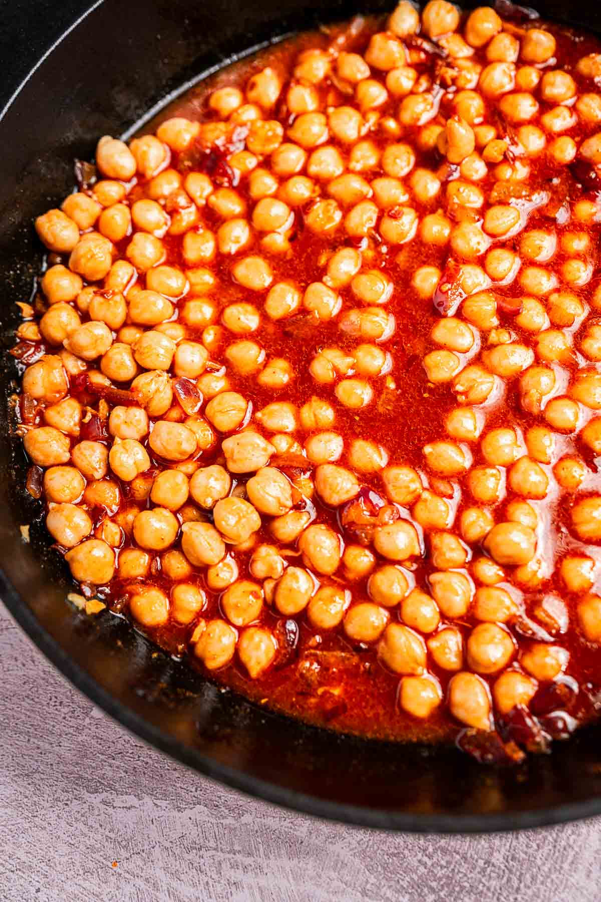 A savory blend of spinach and chickpeas simmering in a black pan, enveloped in a rich red sauce.